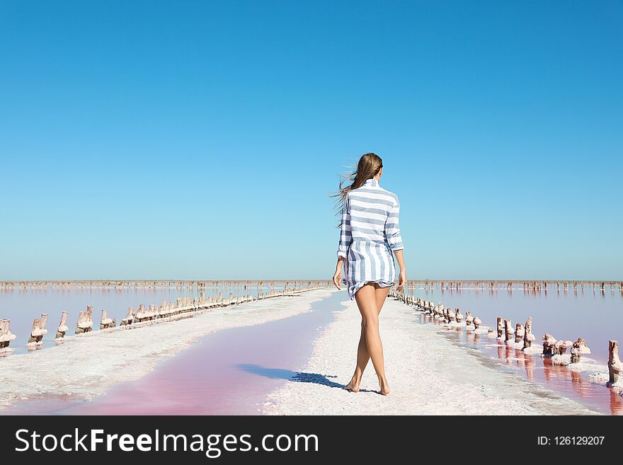 Beautiful woman posing near pink lake