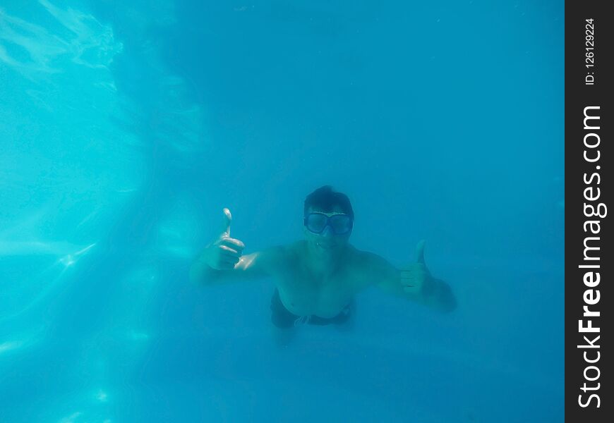 Young man having fun underwater in swimming pool
