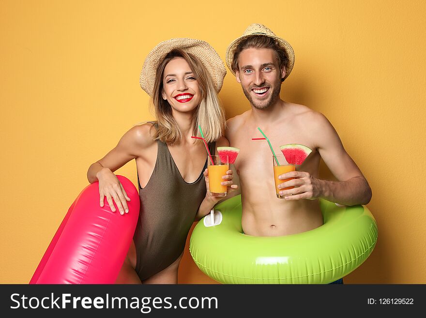 Happy young couple in beachwear with inflatable rings