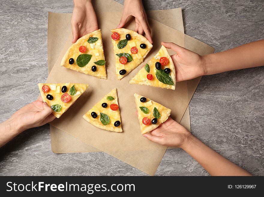 People taking tasty homemade pizza slices from table, top view