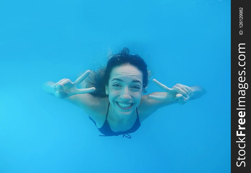 Beautiful young woman swimming in pool, underwater view