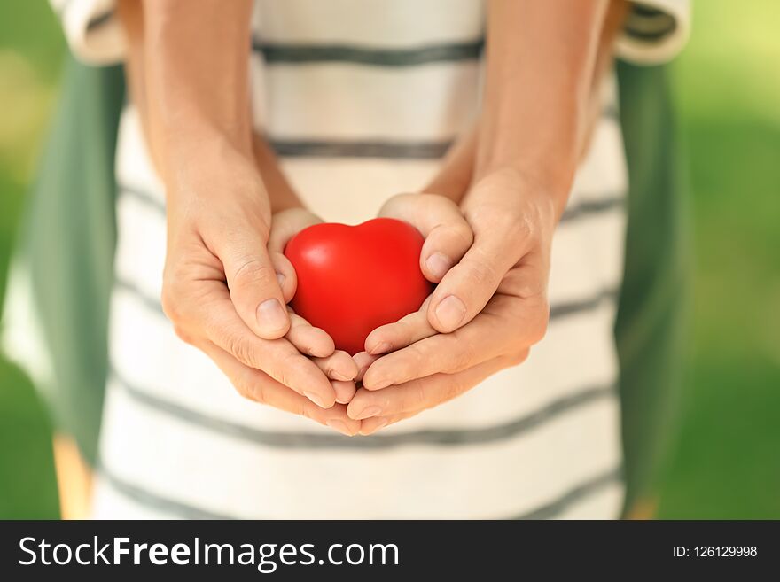 Adult and child hands holding heart on blurred background, closeup. Family concept