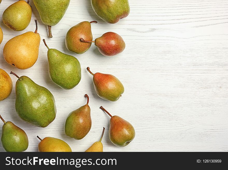Ripe pears on white wooden background, top view. Space for text