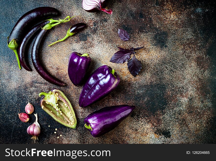 Raw purple seasonal vegetables over rustic background. Top view, flat lay, copy space. Raw purple seasonal vegetables over rustic background. Top view, flat lay, copy space