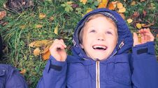 Little Kid Boy Lying In Autumn Leaves In Blue Jacket. Happy Child Having Fun In Autumn Park On Warm Day. Cute School Boy Royalty Free Stock Photo