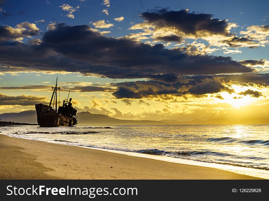 An old abandoned shipwreck, wrecked boat sunken ship stand on beach coast. Scenic sunset sky. An old abandoned shipwreck, wrecked boat sunken ship stand on beach coast. Scenic sunset sky