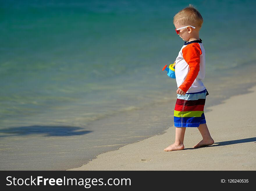 Two year old toddler boy playing with beach toys on beach. Two year old toddler boy playing with beach toys on beach