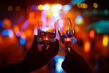 Wineglass Of Champagne In Woman Hand And A Glass Of Whiskey In A Man Hand Against A Background Of Colored Lights Royalty Free Stock Images