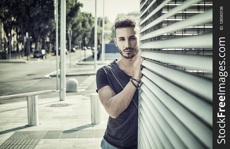 One handsome young man in urban setting in European city, wearing jeans and black t-shirt. One handsome young man in urban setting in European city, wearing jeans and black t-shirt