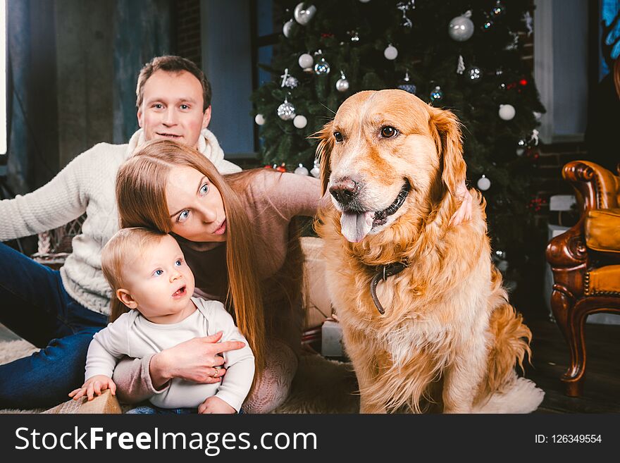 Theme Christmas and New Year family circle and domestic pet. Mom dad and child 1 year old Caucasian woman sitting on floor near Ch