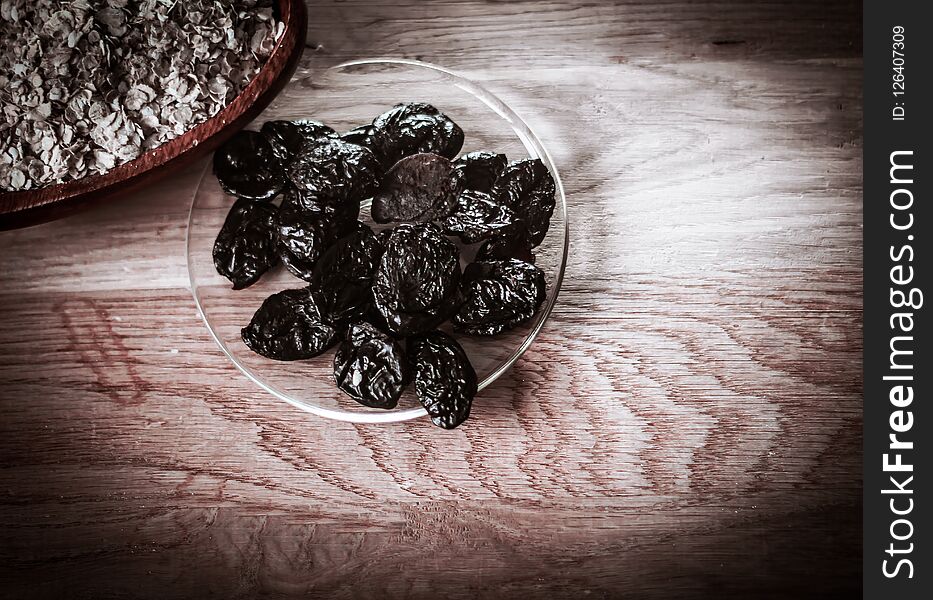 Prunes in a bowl and cereal on a wooden table