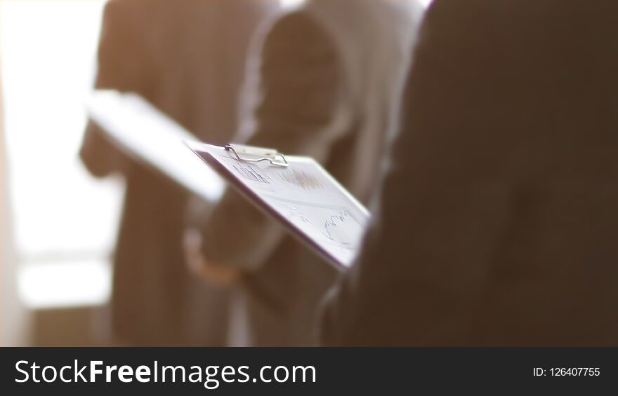 Close up.businessman with a clipboard on the background of colleagues.