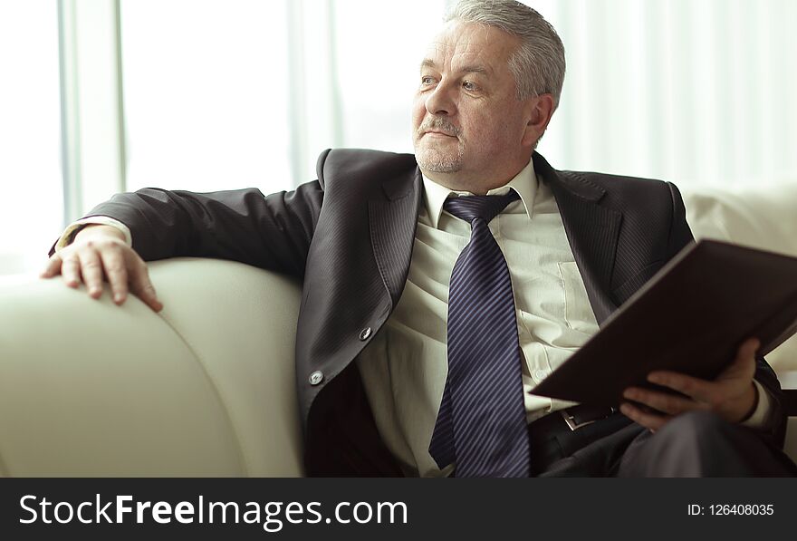 Boss with clipboard sitting on the office couch.business concept.