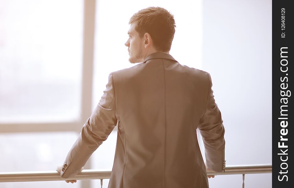 Rear view. businessman in casual wear standing and thinking near the office window