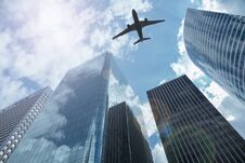 Airplane In The Sky With Modern Buildings Royalty Free Stock Photos