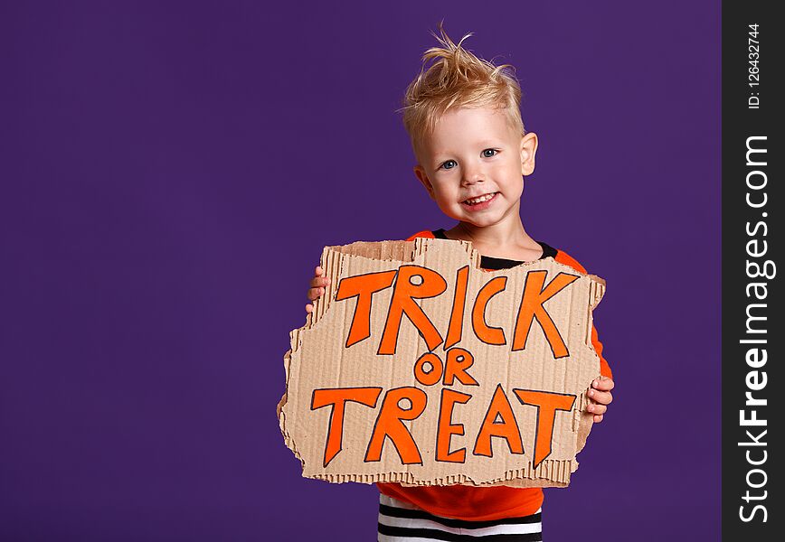 Happy Halloween! cheerful child boy in costume with pumpkins on a violet purple background