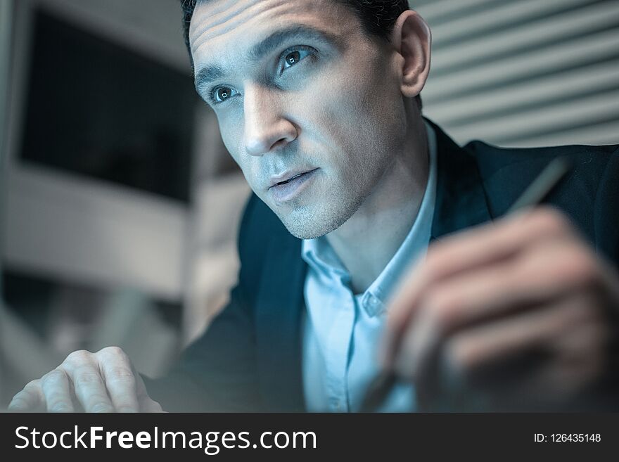 Important information. Portrait of young concentrated man making notes holding a pencil