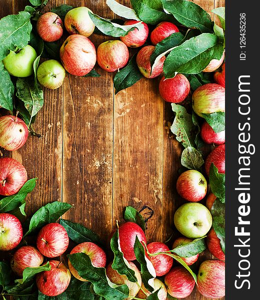 Ripe red apples with leaves on wooden background. Shallow dof. Ripe red apples with leaves on wooden background. Shallow dof.