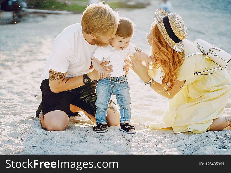 Beautiful red-haired women with her husband and a wonderful son sitting on a summer beach on the sand. Beautiful red-haired women with her husband and a wonderful son sitting on a summer beach on the sand