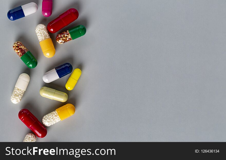 Closeup different medicine capsules and pills on grey background. Closeup different medicine capsules and pills on grey background