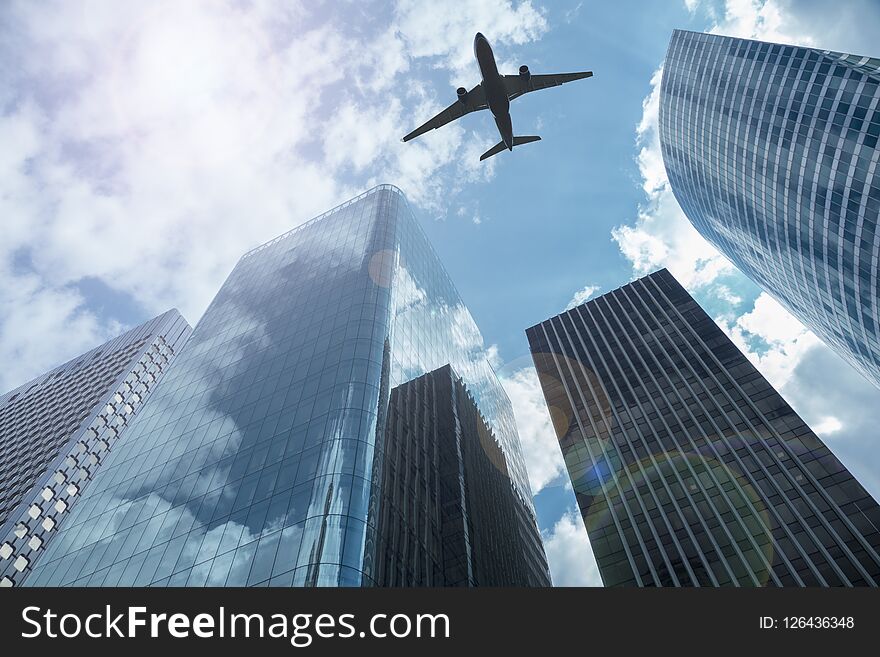 Airplane in the sky with modern buildings, with a blue sky