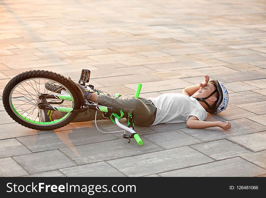 Little boy fallen off his bicycle on street