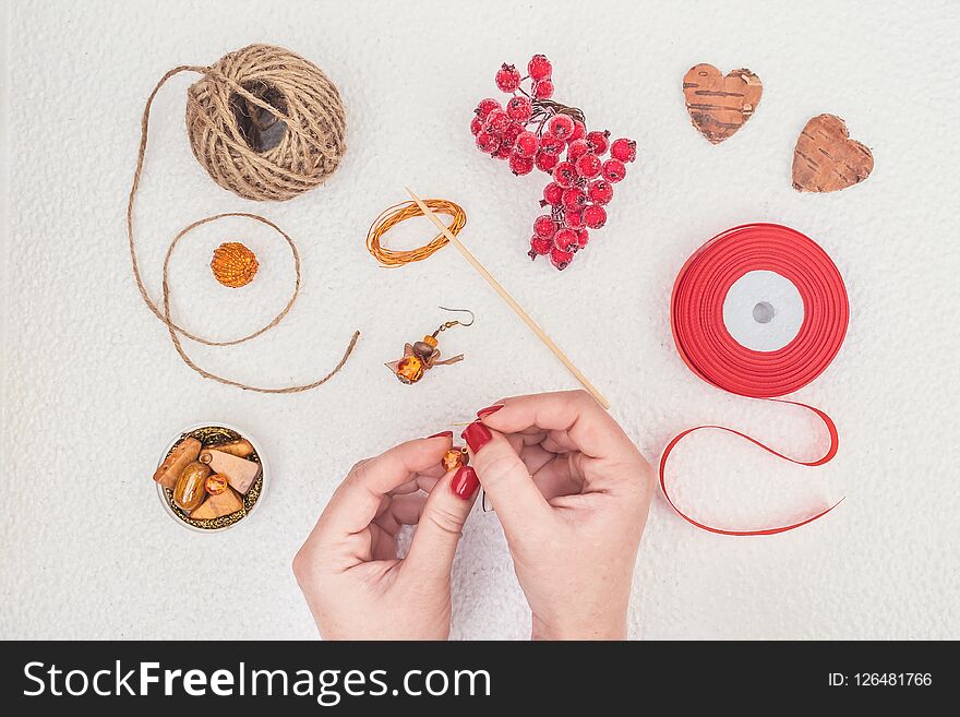 Handmade Jewelry, DIY flat lay in red and brown. Jewelry designer workplace. Woman hands making handmade earrings with amber.