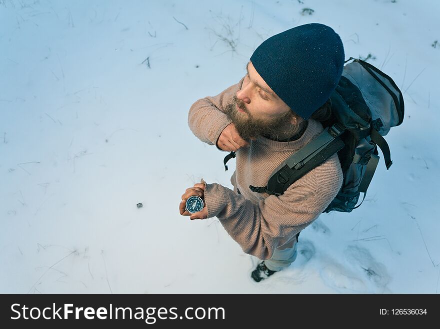 Traveller with compass in winter forest