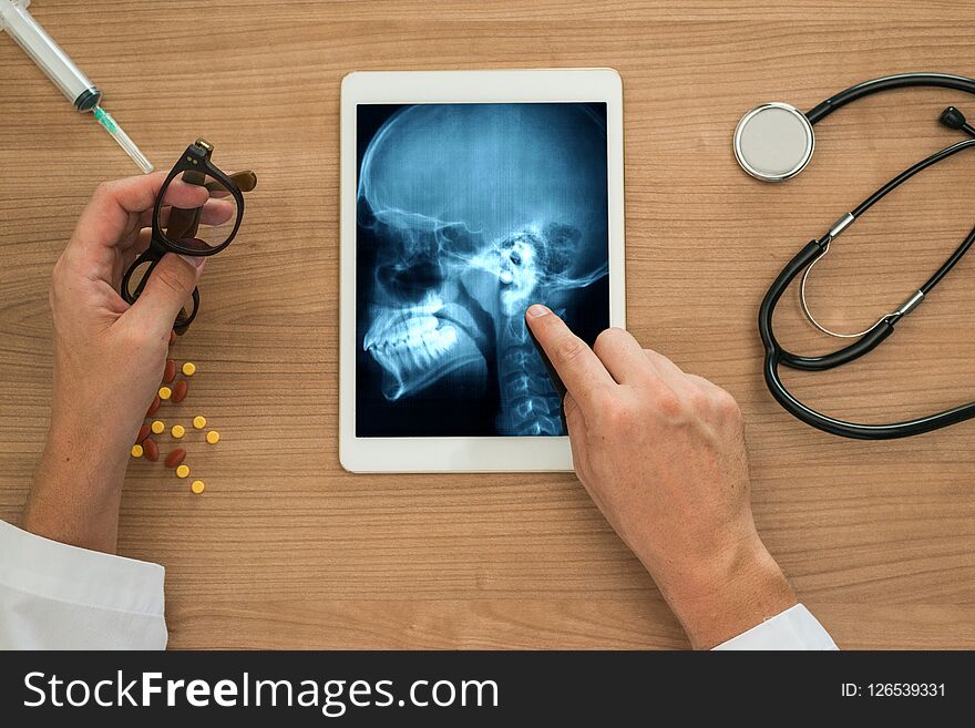 Hand of a doctor showing a xray of ears and skull on a digital tablet