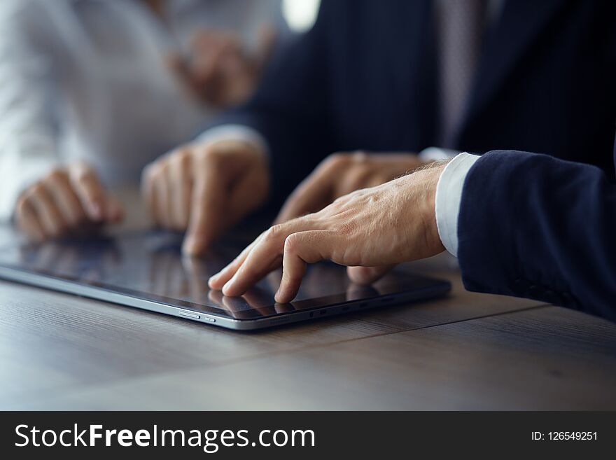 Business people standing at table and touching tablet. Discussing new project. Team business concept. Business people standing at table and touching tablet. Discussing new project. Team business concept.