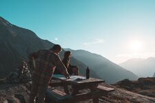 Coouple Hikers Reading Trekking Map On Table In Backlight, Rear View. Adventure Exploration On The Alps. Stock Photo