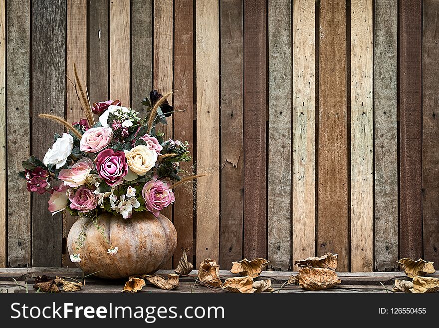 Flower and pumpkin on wooden background with leaves on the ground. Flower and pumpkin on wooden background with leaves on the ground