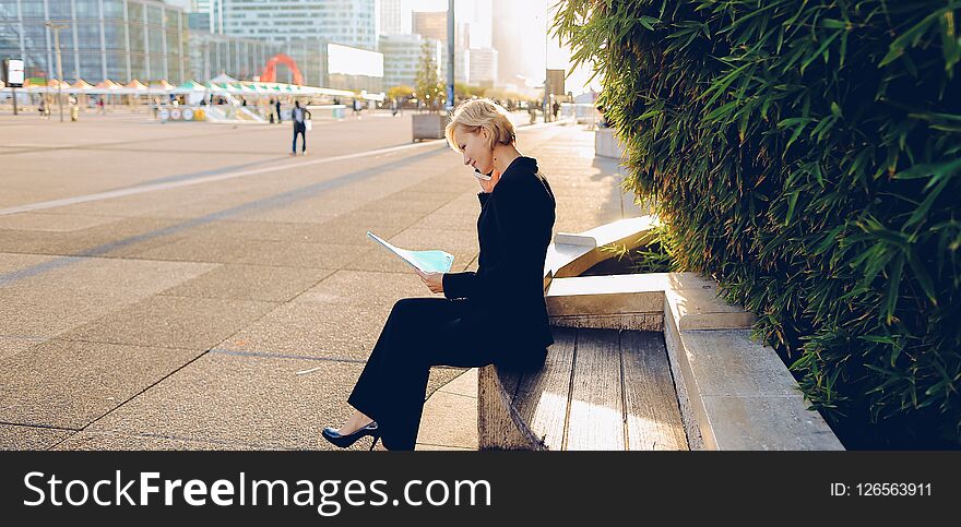 Secretary talking by smartphone with document case in outdoors
