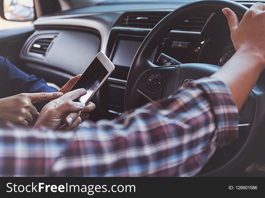 Two People Using Map On Smart Phone In A Car.