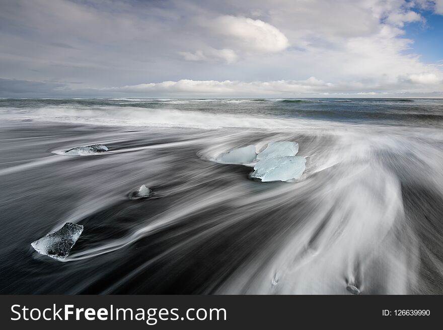 Iceland Diamond Beach, Glacier Lagoon icebergs form abstract shapes in the ocean at Black diamond beach, Jokulsarlon, Iceland. Amazing landscape at sunset in a stormy day.