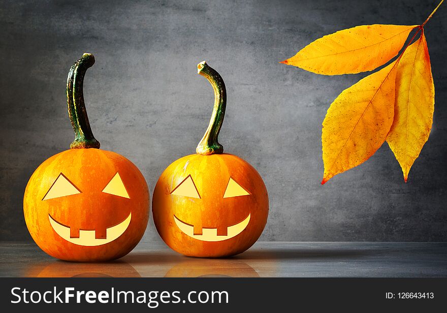 Halloween pumpkin lantern with dry leaves with black background.