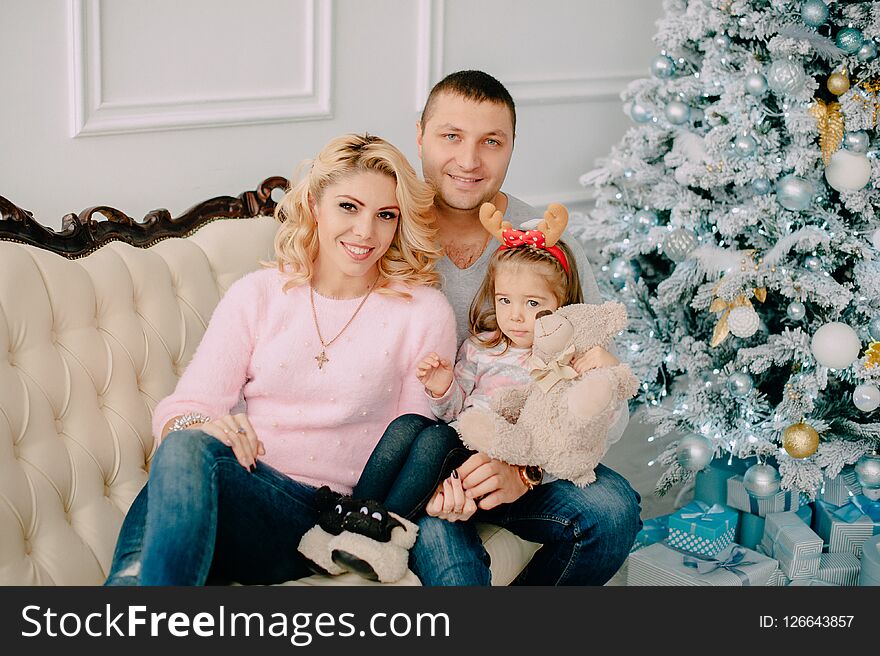 Young family sitting on sofa near Christmas tree