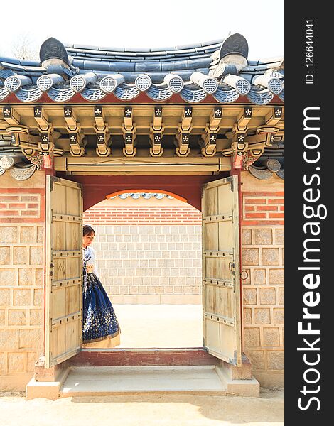 Beautiful Korean Woman Dressed Hanbok Passing The Traditional Door In Palace.