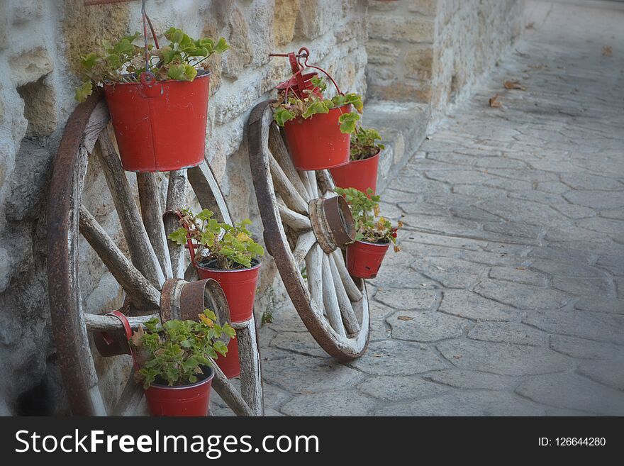 Wheels And Red Flowerpots In Afytos
