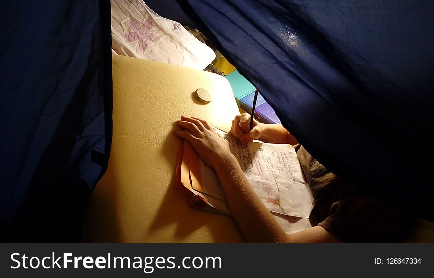 Child, kid, homeschooler learns writes studies in a tent at home or traveling, writing hand. Child, kid, homeschooler learns writes studies in a tent at home or traveling, writing hand