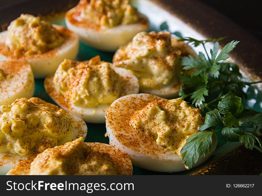Deviled eggs on a plate with paprika and parley to the side. Deviled eggs on a plate with paprika and parley to the side