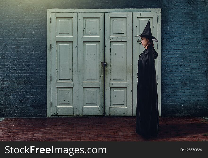 Woman In Black Scary Witch Halloween Costume With Old Brick Wall