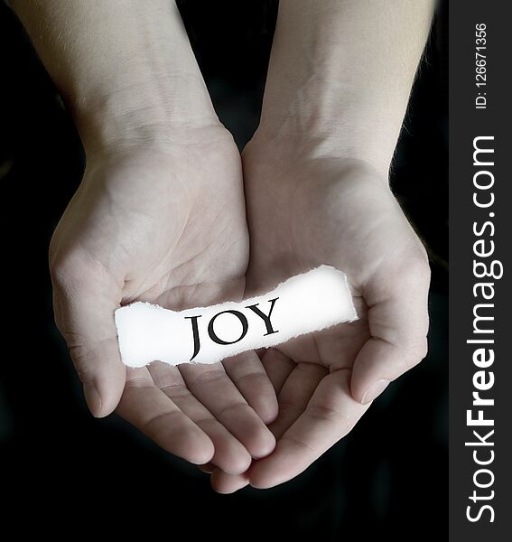 Hands holding joy word sign on paper illustrating choosing to be happy. Hands holding joy word sign on paper illustrating choosing to be happy