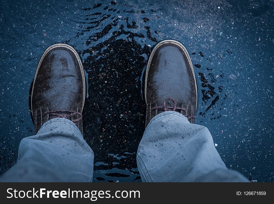 Standing in the middle of puddle during rainfall