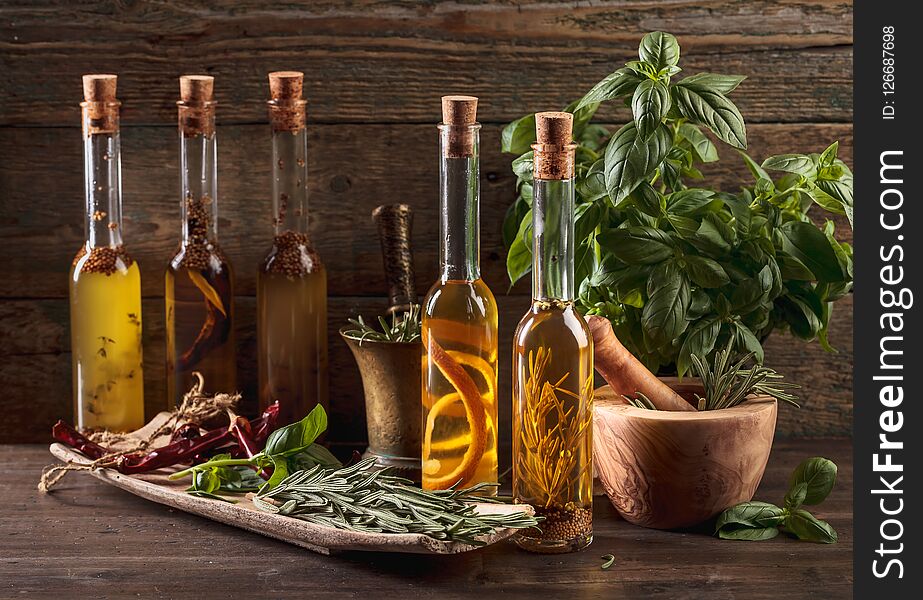 Olive oil with different spices and herbs on a old wooden table. Olive oil with different spices and herbs on a old wooden table.