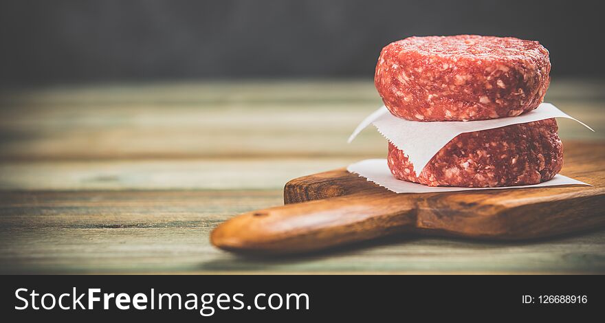 Raw burgers - cutlets from organic beef meat on wooden background, space for text