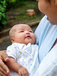 Portrait Of Happy Asia Mother Holding His Newborn Sweet Baby Dressed. The Mommy Embracing Her Baby With Love And Care. Her Daughte Stock Photo
