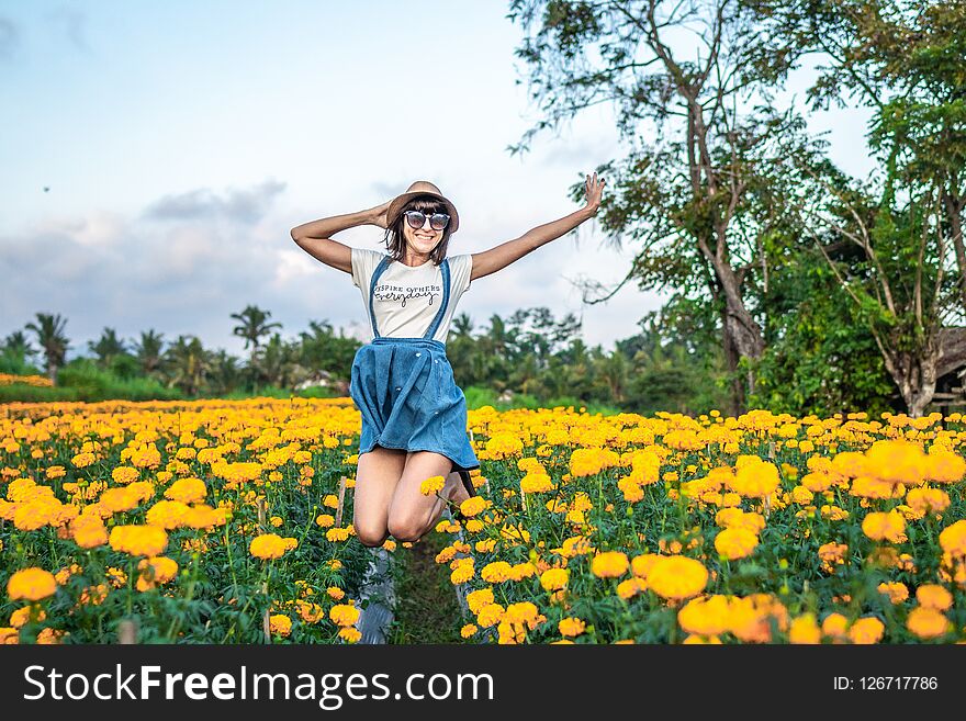 Close up portrait of happy and beautiful young woman relaxing enjoying the fresh beauty of gorgeous orange marigold