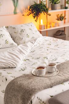 A Mood Created By A Night Lamp Standing Beside A Bed Dressed In Green Plants On White Pattern Linen And Pillows In A Natural Style Stock Photography A Mood Created By A Night Lamp Standing Beside A Bed Dressed In Green Plants On White Pattern Linen And Pillows In A Natural Style Stock Photography