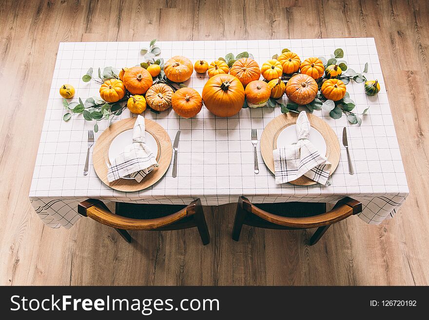 White table with dishes and food in the room. Yellow pumpkins on the table in cafe. Celebrating of Halloween